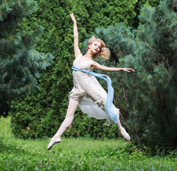 Beautiful girl dressed in a tunic jumping in summer park