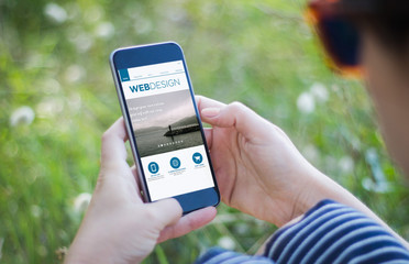girl in grass holding her smartphone with web design interface