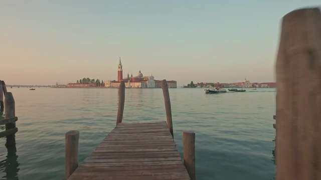 Parking gandolas on the Doge's palace embankment with the bell tower of the Saint Giorgio Maggiore church view.