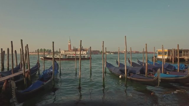 Parking gandolas on the Doge's palace embankment with the bell tower of the Saint Giorgio Maggiore church view.