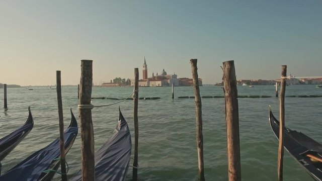 Parking gandolas on the Doge's palace embankment with the bell tower of the Saint Giorgio Maggiore church view.