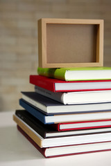 stack of new books with wooden photo frame