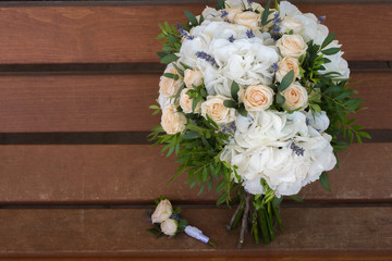 Beautiful bridal bouquet and boutonniere on a wooden bench