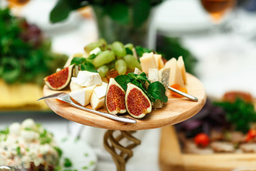 Exotic fruits and cheese lie cut on a wooden tray