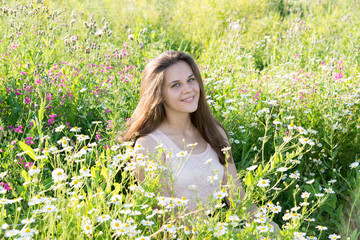 girl sits on meadow with wild flowers