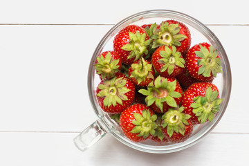 Glass cup full of strawberries on table