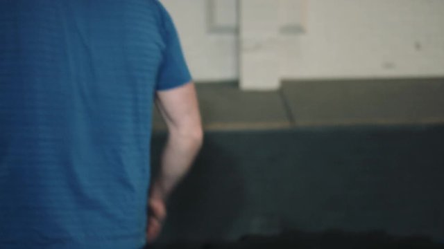 Young man lifting big wheel in bootcamp gym