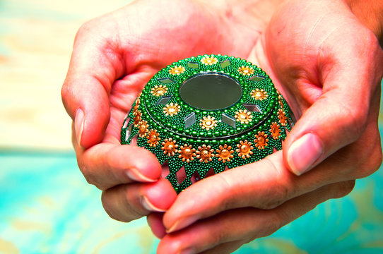 Woman's hands holding green oriental casket