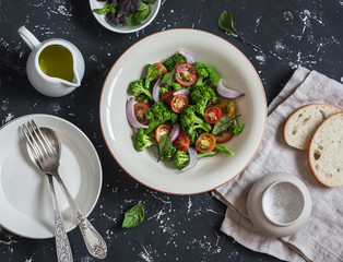 Fototapeta na wymiar Fresh salad with broccoli and tomatoes on a dark background. Healthy vegetarian food