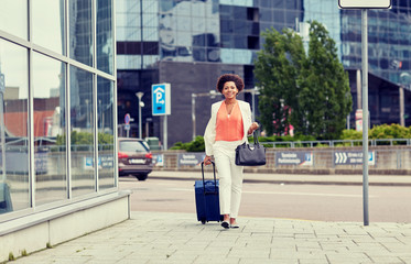 happy young african woman with travel bag in city