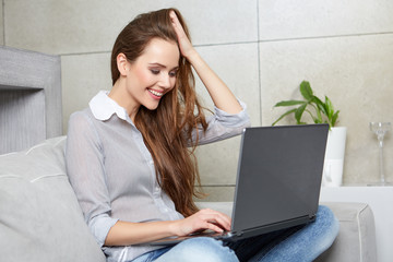 Woman using a laptop while relaxing on the couch