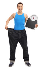 Guy in large jeans holding a weight scale