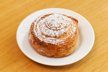 Powdered sugar sweet roll bun on table