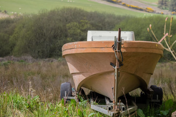old abandoned boat on trailer in a grassy filed