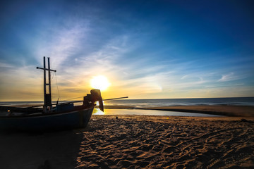 beautiful sunset sunrise background on the beach with silhouette boat in the foreground