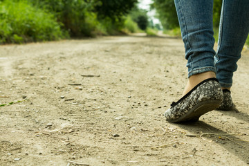 The girl goes on a dirt road through the trees