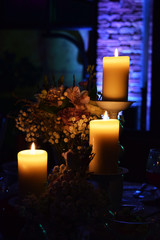 Three сandles in the dark, bouquet of flowers in a vase, wedding decor