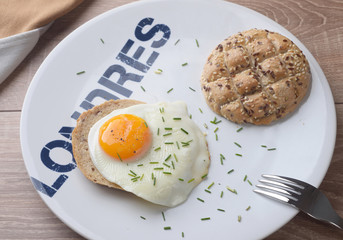 Scrambled eggs sunny side up on bread. Breakfast on a white plate.