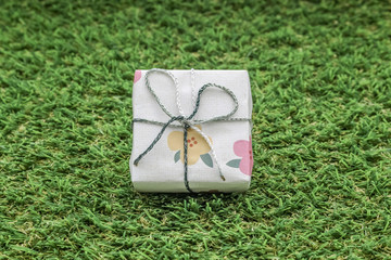 isolated white gift box with silver ribbon on green grass background
