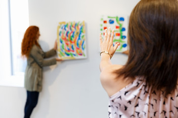 Young artists in gallery hanging painting on walls