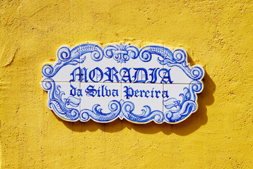 Traditional  plate with street name on yellow wall,Goa