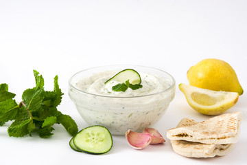 Tzatziki in bowl and ingredients isolated on white background
