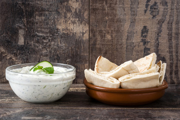 Tzatziki sauce in bowl on rustic wooden background


