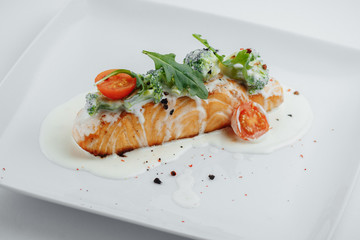 red fish on a white plate with tomato sauce and broccoli