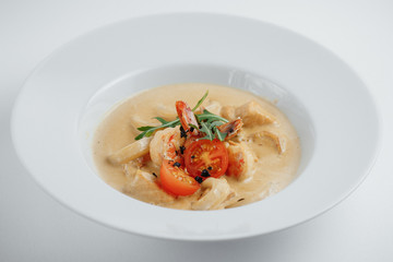 seafood soup with tomatoes and arugula in the white plate