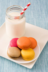 Milk and colored macaroons on blue background

