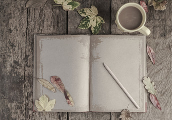 coffee mug and notebook on wooden table decorated with autumn leaves