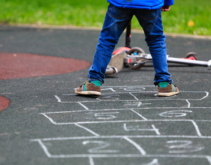 kid playing hopscotch on playground outdoors