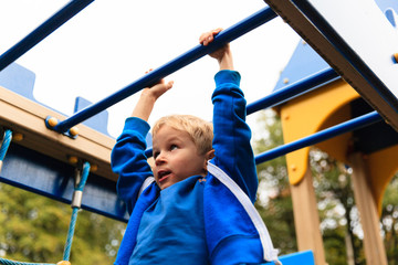 little boy playing on monkey bars in autumn