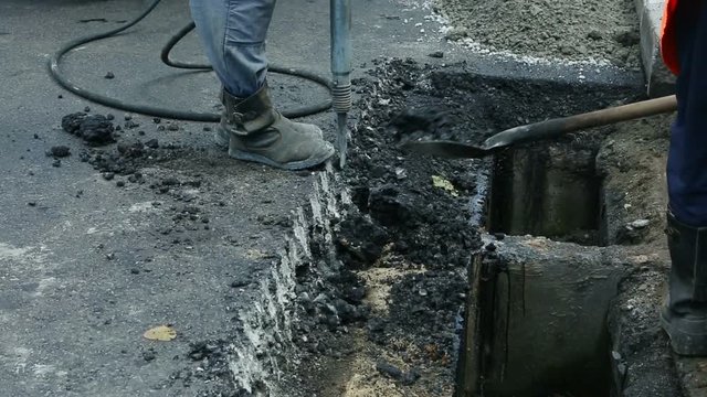 Road Paving. Workers laying stone mastic asphalt during street repairing works. Worker making asphalt with coated chippings. Drainage repair, installation of manhole