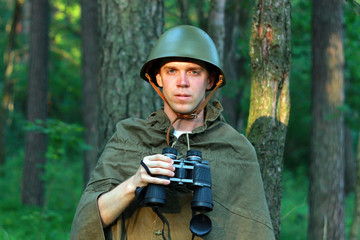 Военный солдат разведчик с биноклем в лесу