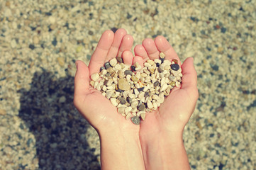 Heart from sea a pebble in female hands. Festive love background
