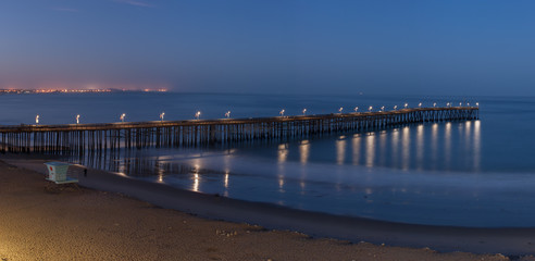 Fototapeta premium Panoramic view of pier illuminated by lamps at dawn.