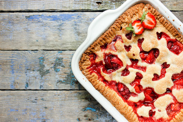 Homemade strawberry pie on old wooden background