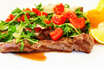 Grilled steaks with fresh rucola, tomatoes and parmesan cheese