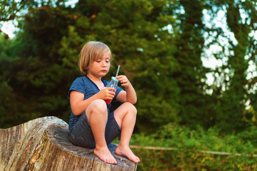 Fototapeta premium Cute little boy drinking smoothie shake outdoors