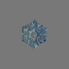 Snowflake isolated on uniform grey background. This is macro photo of real snow crystal with hexagonal shape, broad arms and several frozen bubbles of rime on surface.