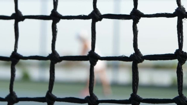Girl tennis player expecting the tennis ball on court, net in front. Dolly shot