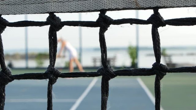 Professional player expecting the tennis ball on court, net in front. Dolly shot