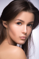 Obraz premium Closeup portrait of beautiful girl with clear healthy skin. Looking at the camera over shoulder. perfect fashion model studio photo
