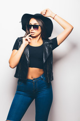 beautiful fashion girl wearing sunglasses and black hat over a white background.