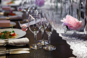 Cutlery at Banquet table covered in natural crocodile skin. Glasses and plates, forks and knives, napkins and buttons for a luxurious celebration in anticipation of guests. Luxury festive table.