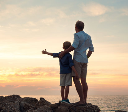 Father and son looking on sunset at the sea