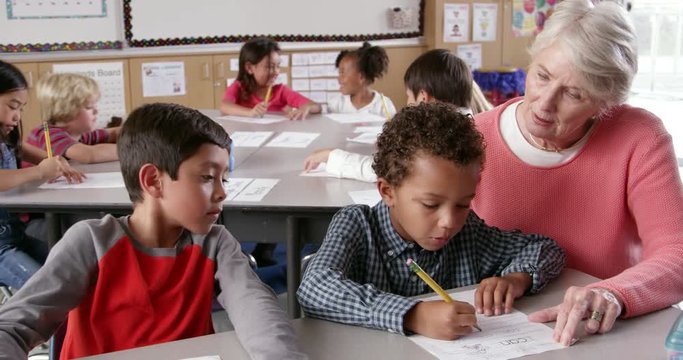 Senior teacher helping young schoolboys with class work