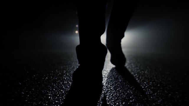 silhouette of mystery man walking into dark night. spooky mystical background.