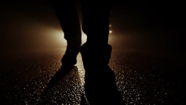 silhouette of feet walking into dark night. spooky mystical background.
